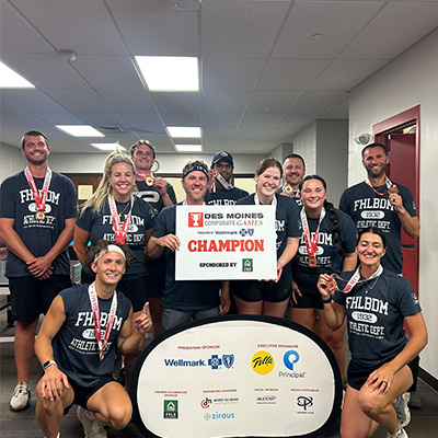 A group of people smiling with medals and a sign that says "Champion" 